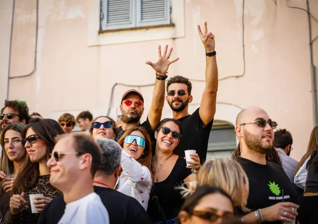 Gruppo di amici che festeggia con le mani alzate tra la folla