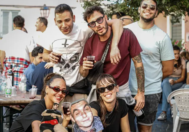 Gruppo di amici con bicchieri di vino e maschere buffe di cartone