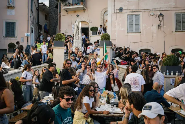 Gruppo di giovani in festa nella piazza del paese con bandiera tricolore
