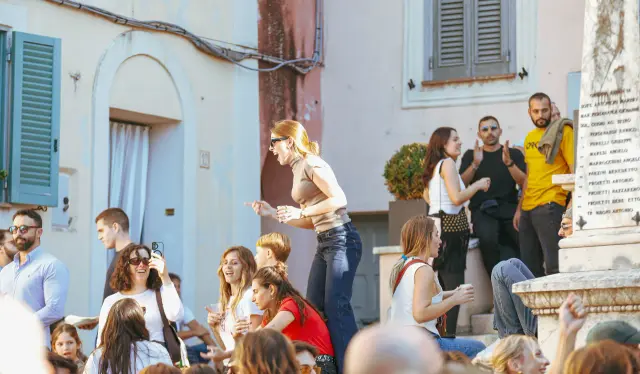 Gruppo di visitatori in festa vicino al monumento della piazza, tra musica e brindisi