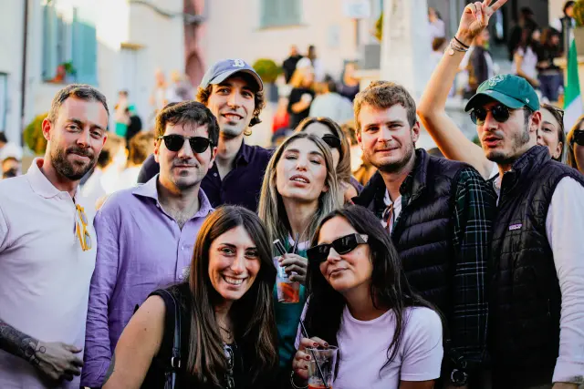 Grande gruppo di amici in posa con bicchieri di aperitivo nella piazza