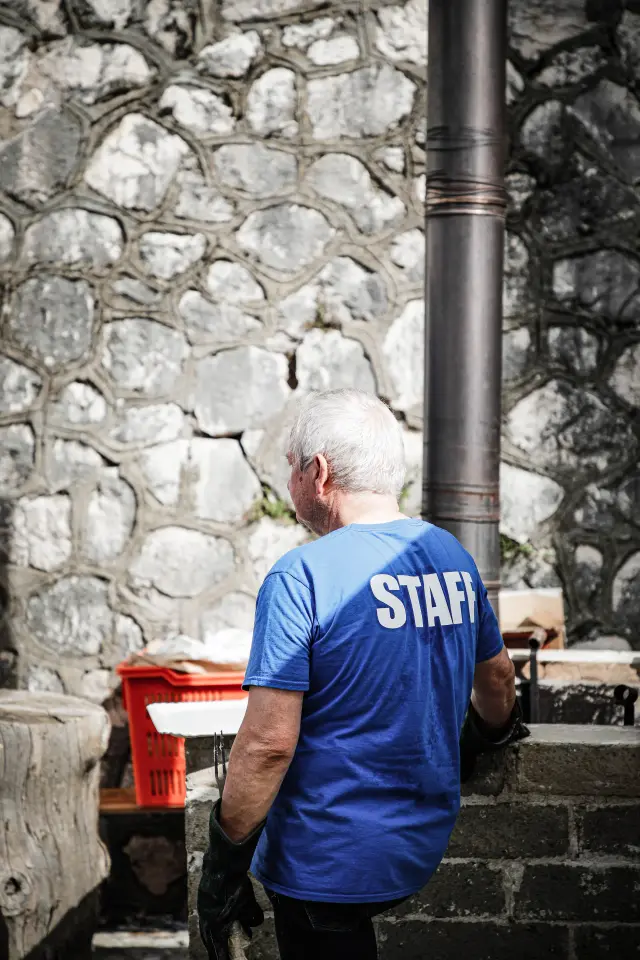 Membro dello staff visto di spalle davanti al muro in pietra