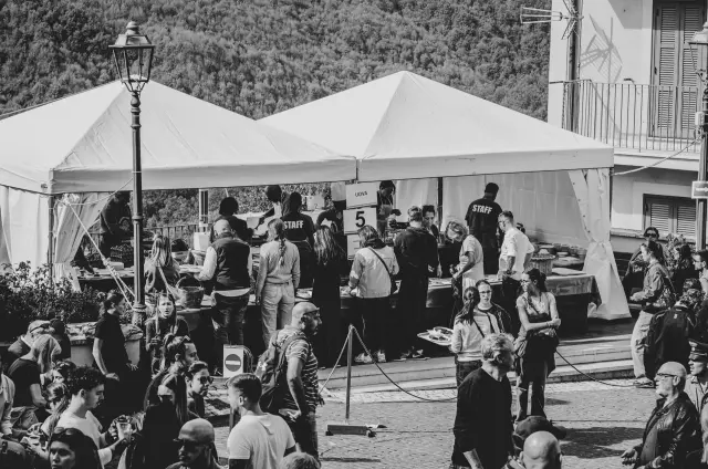 Vista in bianco e nero degli stand gastronomici sotto i gazebo con la folla della sagra