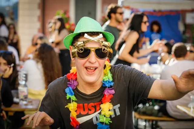 Visitatore in costume da festa con occhiali stravaganti e collana di fiori colorata