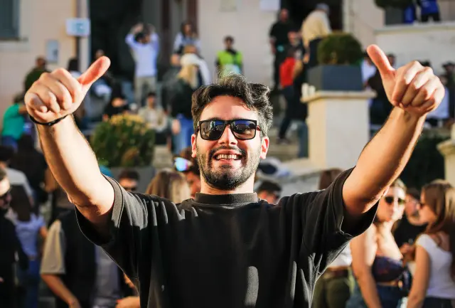 Visitatore sorridente con i pollici alzati tra la folla della sagra