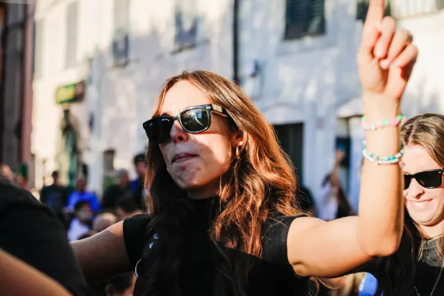 Visitatrice con occhiali da sole che esulta con il pugno alzato tra la folla