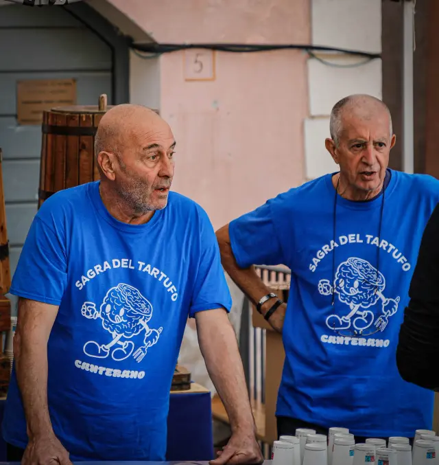 Due volontari con la maglietta blu "Sagra del Tartufo Canterano" al banco vendita