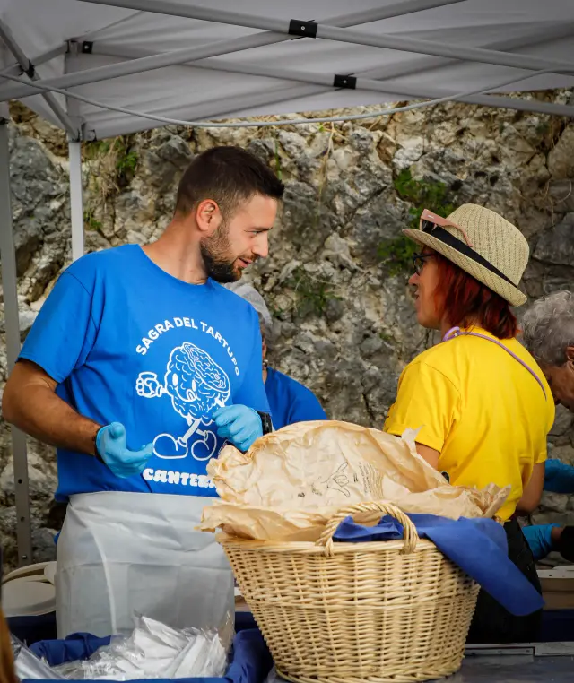 Volontari che si scambiano un cesto di vimini allo stand della sagra