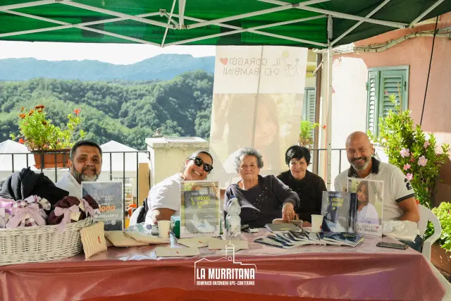 Gruppo di volontari sorridenti al banco informativo dell'associazione benefica "Il coraggio dei bambini"