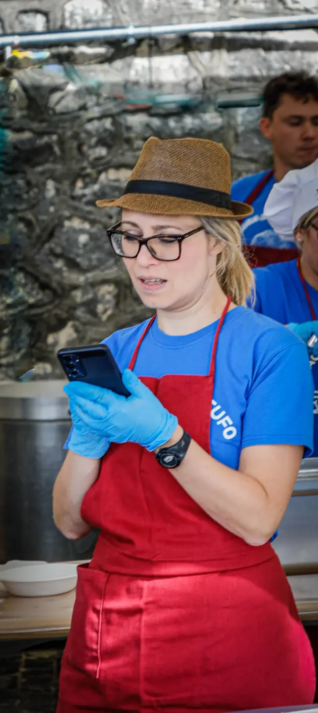 Giovane volontaria con cappello e grembiule rosso che controlla il telefono