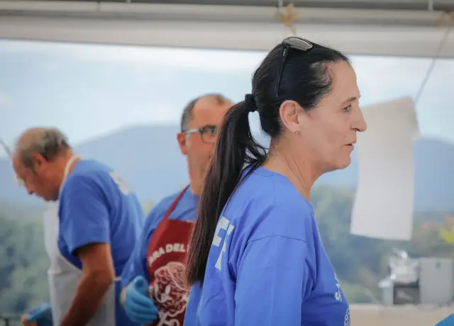 Volontaria di profilo con maglietta blu nella tenda cucina della sagra