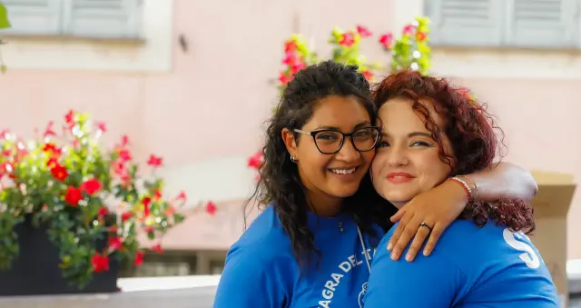 Due volontarie dello staff abbracciate con indosso le t-shirt della Sagra del Tartufo