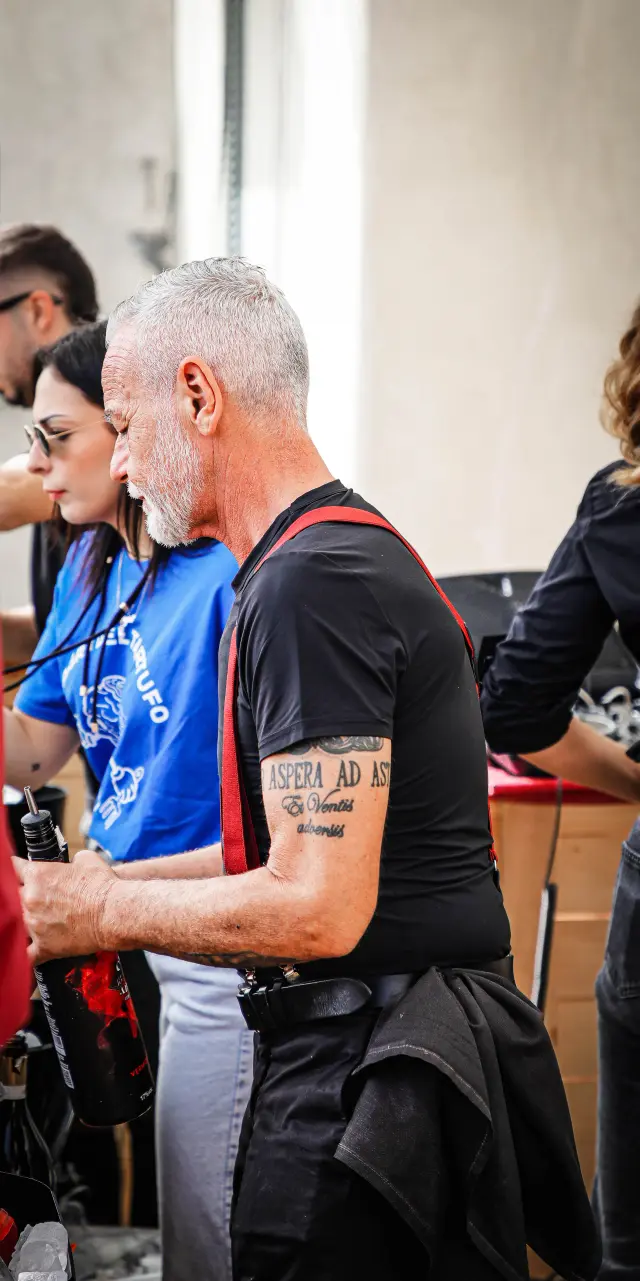 Volontario con bretelle rosse e tatuaggio sul braccio, ritratto di profilo